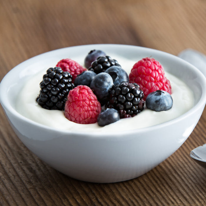 Bowl of flavoured yogurt topped with fresh berries and grapes