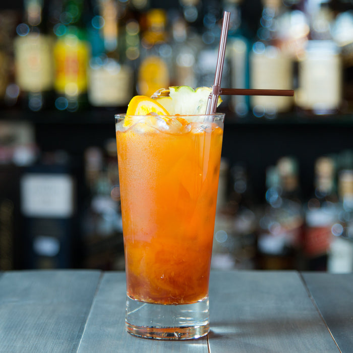 Orange and peach mocktail garnished with a slice of ginger.