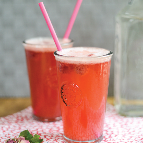 Raspberry, rose and mint gin fizz garnished with fresh raspberries.