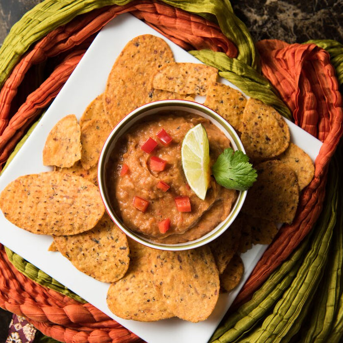 Roasted red pepper and cannellini bean dip in a bowl, ready to serve with veggie sticks.