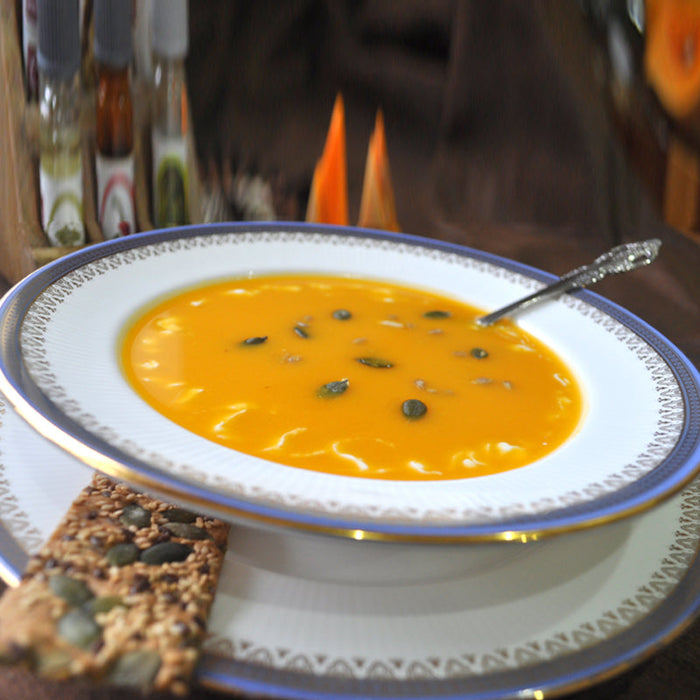 Bowl of butternut squash and sweet potato soup with a cream swirl and pumpkin seeds