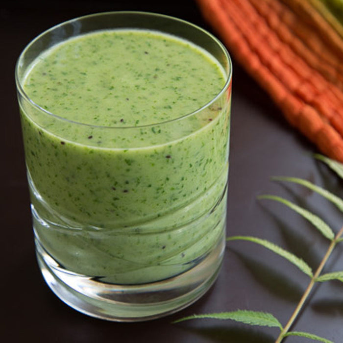 Fresh green smoothie in a glass, blended with fruit, spinach and a sprinkle of chia seeds